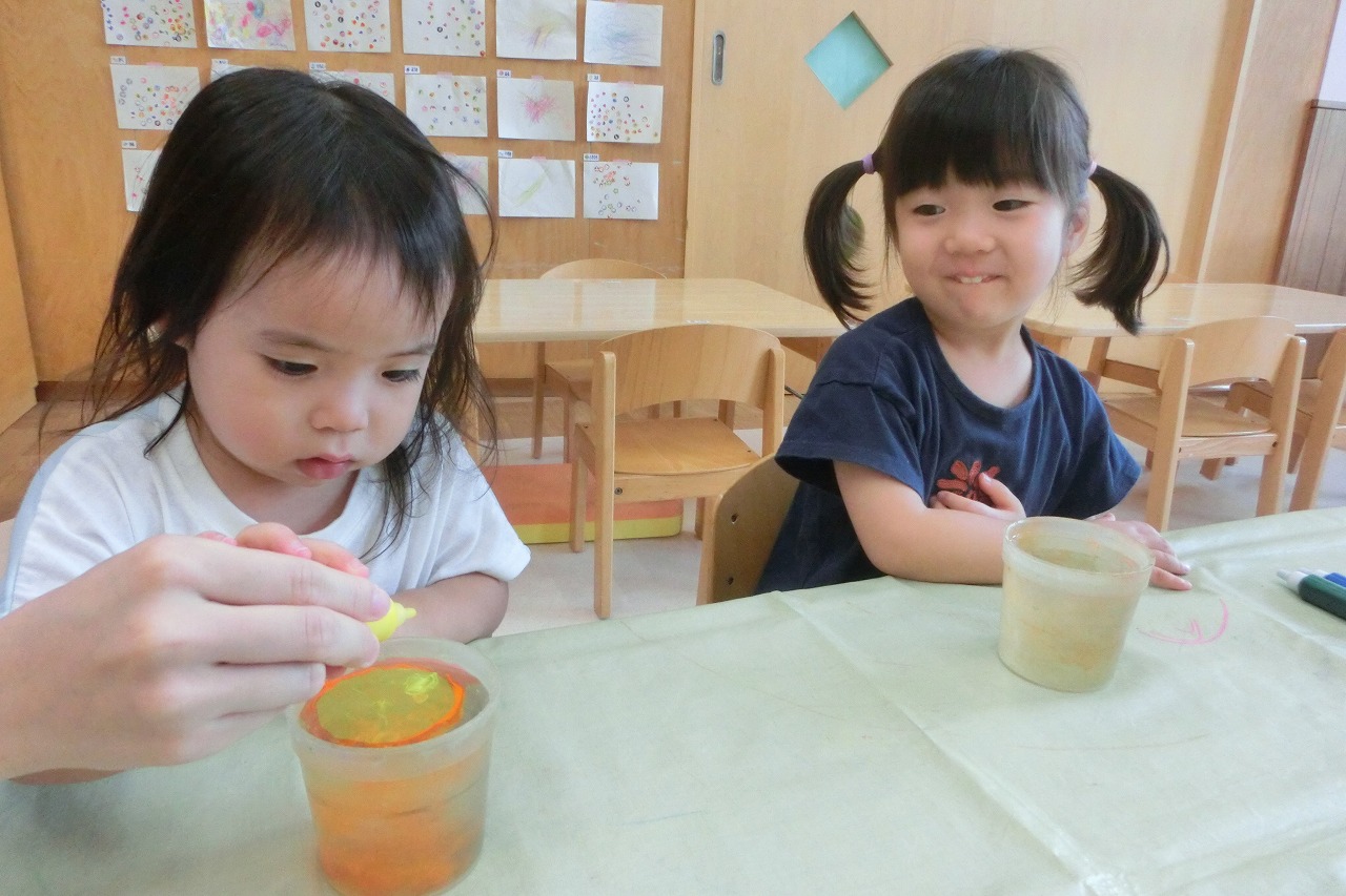 スポイトで水を張ったカップに色素を垂らしている様子
